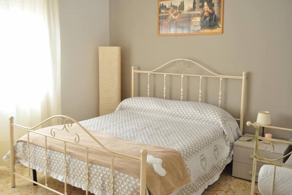 A neatly made bed with a patterned bedspread and a wooden headboard.