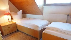 A bedroom with two beds, a nightstand, a lamp, and a wooden ceiling. - Schwarzwaldblick by Interhome (Schonach)