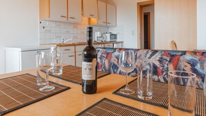 A modern kitchen with wooden cabinets, a dining area with a patterned tablecloth, and a bottle of wine on the table. - Voithofer by Interhome (Königsleiten)