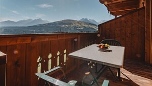 A wooden deck with a table and chairs, overlooking a mountainous landscape. - Voithofer by Interhome (Königsleiten)