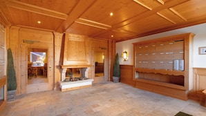 A wooden interior with a fireplace, stone flooring, and a mailbox wall.