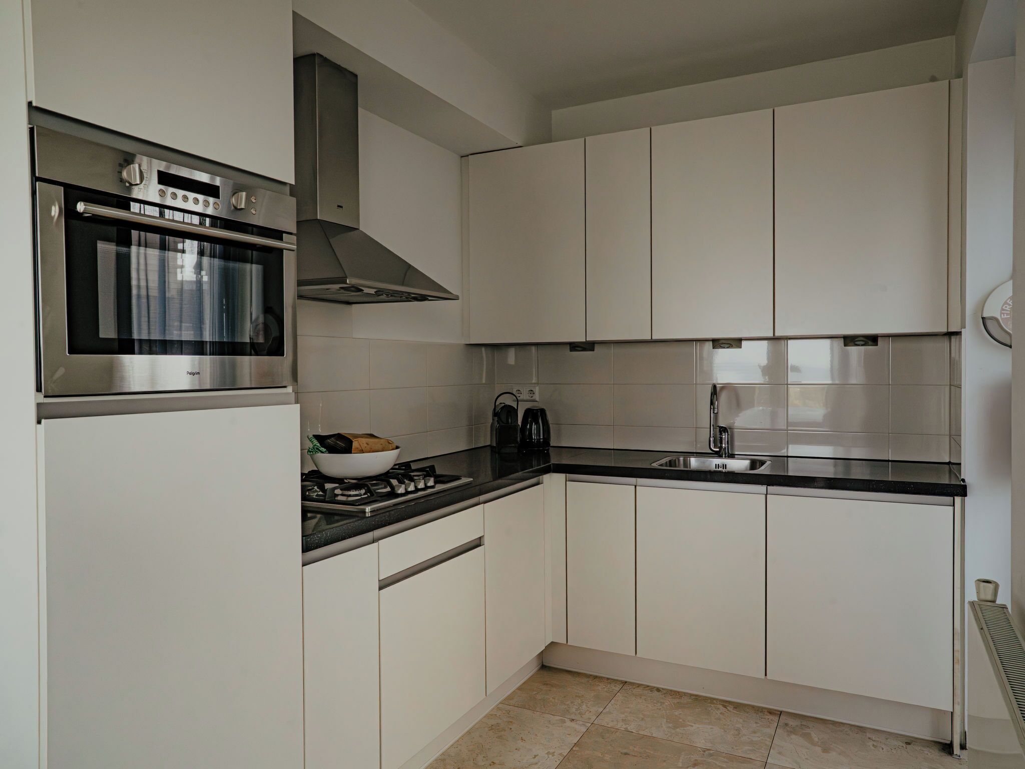 A modern kitchen with white cabinets, a stainless steel oven, and a gas stove.