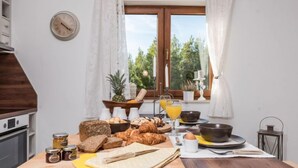 A breakfast table with bread, pastries, and condiments, a clock, and a view of greenery outside. - Velebit by Interhome (Rovanjska)