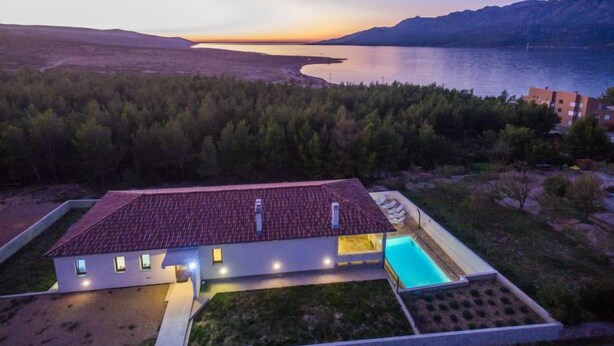 A modern house with a swimming pool, surrounded by a forest and a lake at dusk. - Velebit by Interhome (Rovanjska)
