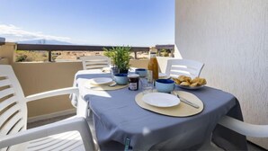 Ein Balkon mit Tisch, Geschirr, Gläsern und einer Flasche, mit Blick auf eine malerische Landschaft.