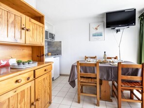 Eine kompakte Küche mit Holzausstattung, einer Mikrowelle und einer Essecke mit Tisch für zwei Personen.