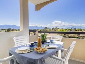 Ein Esstisch auf einem Balkon mit Blick auf Berge und Grünlandschaft.