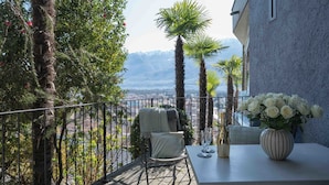A balcony with a table, chairs, and a vase of flowers. - Suite Classic by Interhome (Ascona)