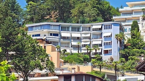 A multi-story hotel with balconies, surrounded by trees and other buildings. - Suite Classic by Interhome (Ascona)