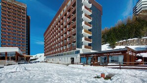 Ein modernes Hotel mit mehrstöckiger Bauweise, Balkonen und verschneitem Gelände.