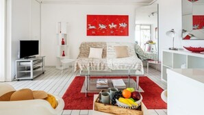 Un salon moderne avec un lit, un téléviseur et un tapis rouge.