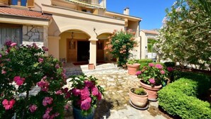 A Mediterranean-style villa with a stone courtyard, potted flowers, and a clear blue sky. - Meridiana by Interhome (Orebić)