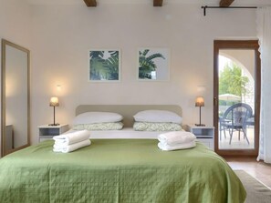 Ett hotellrum med en säng, två vägglampor och två inramade tavlor.