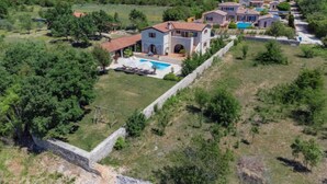 A large villa with a swimming pool, surrounded by lush greenery and a stone wall. - Histria 1 by Interhome (Pula/Vodnjan)