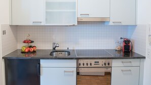 A kitchen with white cabinets, a stainless steel sink, a dishwasher, and a red vacuum cleaner. - Double Room Modern by Interhome (Ascona)