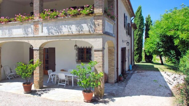 A two-story building with a balcony adorned with flowers, outdoor seating, and potted plants. - Montebello by Interhome (Città di Castello)