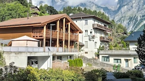 Ein Bergresort mit Chalet-Gebäuden, hölzernen Balkonen und Blick auf schneebedeckte Gipfel.