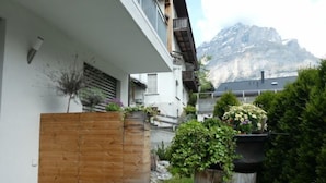 Ein modernes Gebäude mit Holzlattenzaun, Blumentöpfen und Blick auf die Berge.
