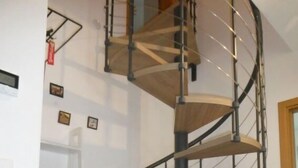 Eine Wendeltreppe mit Holzvertäfelung und Metallgeländern, die zu einer oberen Ebene führt.