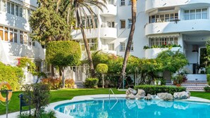 A pool surrounded by lush greenery and white buildings with balconies. - Marbella Real by Interhome (Marbella)