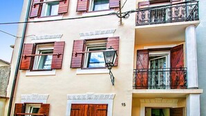 A multi-story building with wooden shutters on windows, a balcony with wrought iron railings, and a street lamp. - Snježana by Interhome (Karlobag)