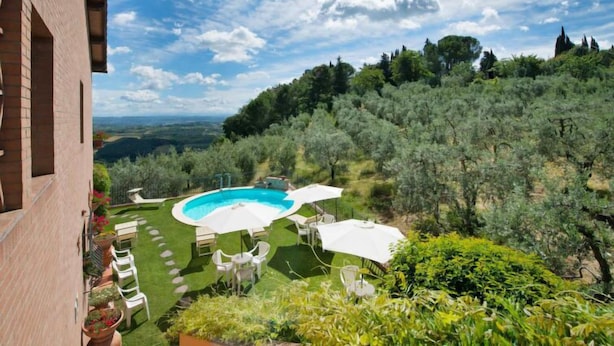 Ein Garten mit Swimmingpool, Gartenmöbeln und Blick auf eine hügelige Landschaft.