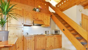 A kitchen with wooden cabinets, a microwave, and a potted plant. - Villa Placidia Apt 32 by Interhome (Canazei)