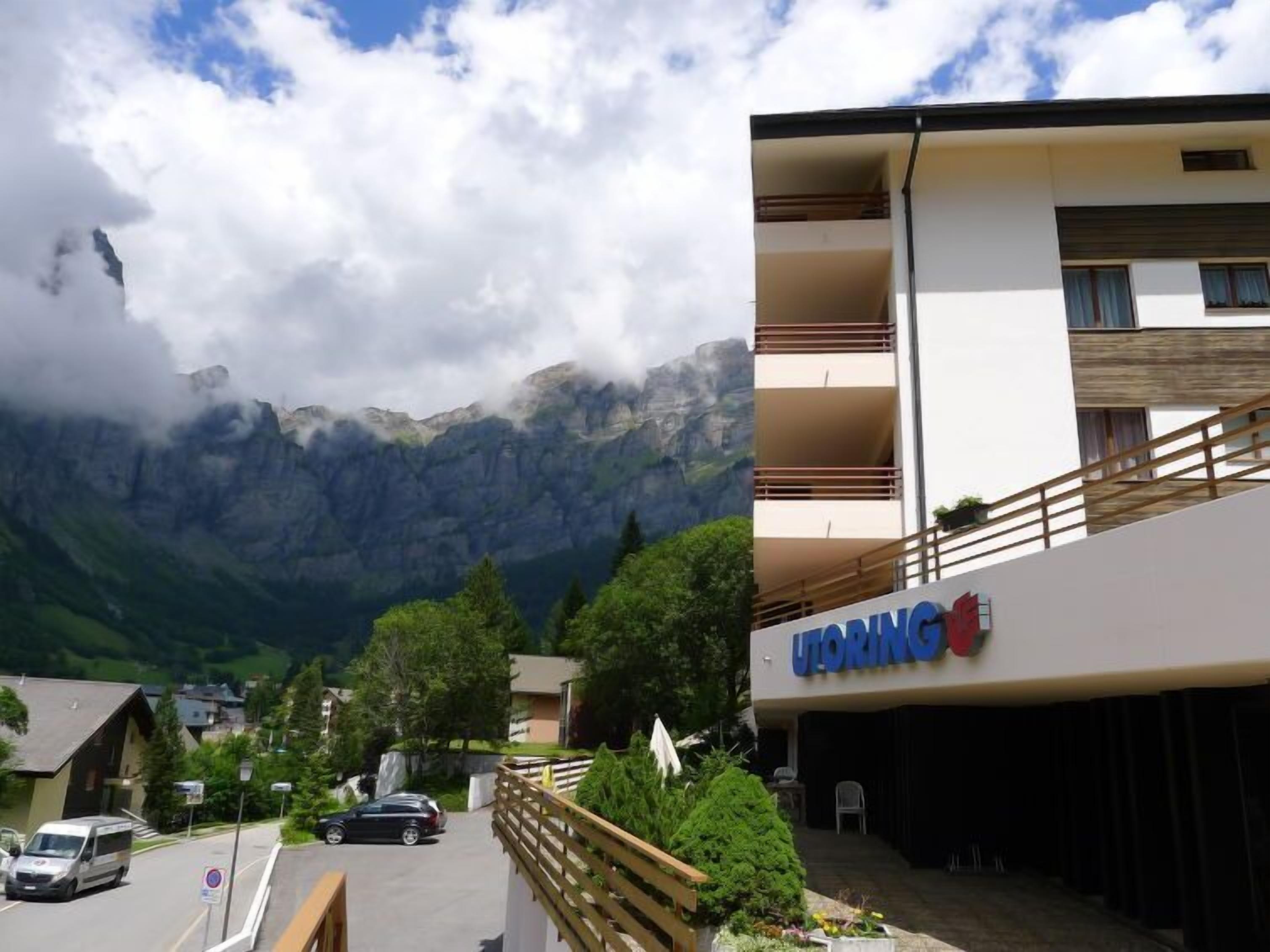A hotel with a mountain view, a parking area, and a building with balconies.