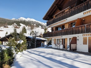A wooden chalet with a balcony, snow-covered ground, and mountains in the background. - Chalet Sunneblick by Interhome (Grindelwald)