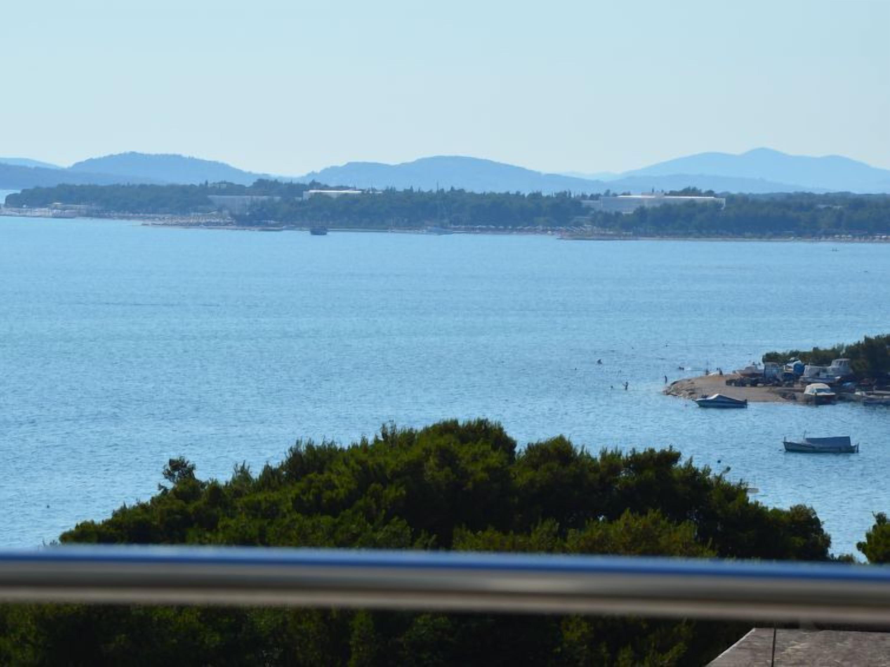En kustvy med klar himmel, en vattenyta och avlägsna berg.