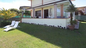 Une maison à deux étages avec un patio couvert, une pelouse et un palmier.