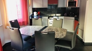 Een kleine keuken met een eettafel en stoelen, een magnetron en een fornuis.