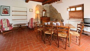 Un comedor con pared de piedra rústica, vigas de madera en el techo y suelo de baldosas.