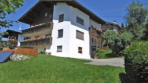 A two-story building with a sloped roof, balconies with flower boxes, and a paved driveway. - Apartment Straif by Interhome (Kirchberg in Tirol)