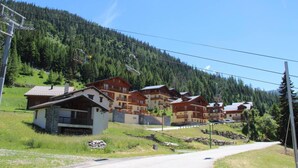 A row of chalet-style buildings with a ski lift in the background, set against a mountainous backdrop. - 300m from ski slopes, floor -1, view mountain, parking, tv, ski locker, 36m², Valfréjus (Valfréjus)
