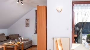 A cozy living room with a wooden dining table, a sofa, and a radiator.