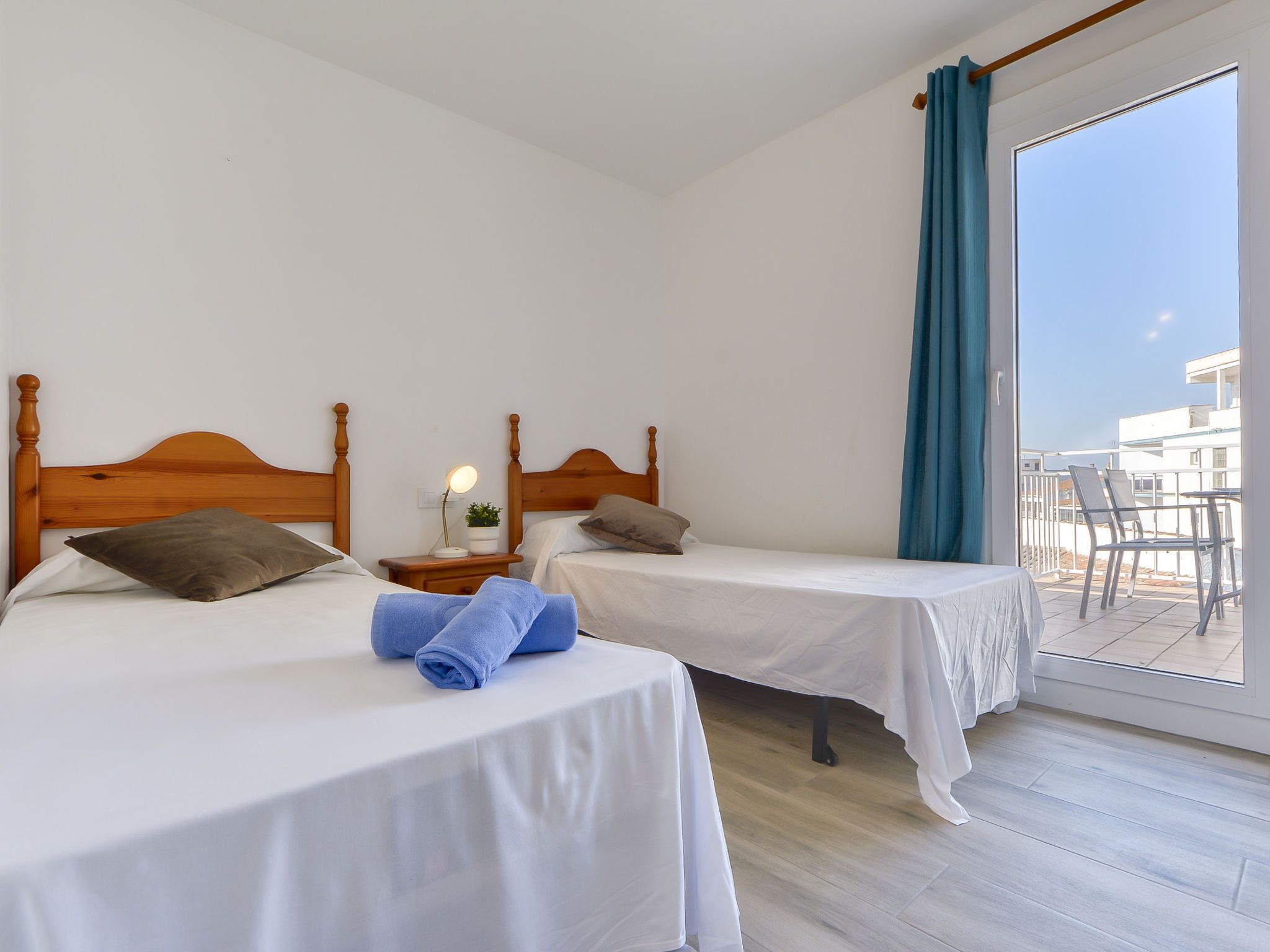 Een hotelkamer met twee houten bedden, een klein nachtkastje met lamp en uitzicht op het balkon.