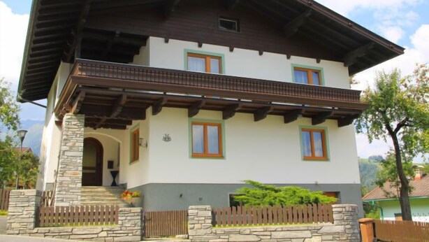 Una casa de dos pisos con balcón, base de piedra y fachada de color claro.