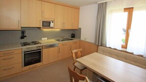Una cocina moderna con armarios de madera, microondas, estufa y comedor con mesa y sillas.