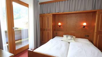 A bedroom with a wooden headboard, two bedside lamps, a bed with white linens, a sliding glass door, and a red carpet.