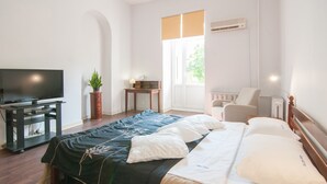 Ein Hotelzimmer mit Bett, Fernseher, Schreibtisch, Stuhl und Fenster.