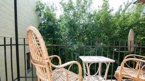 Ein Balkon mit Korbmöbeln, darunter zwei Stühle und ein kleiner Tisch.