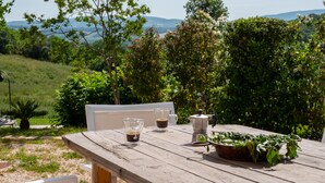 Et træbord med en hvid stol, to kaffekopper og en kaffekande.