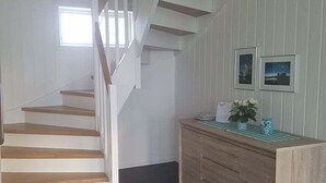 A staircase with wooden steps and white railings leading to a landing. - Lyngsalpan Cruise Lodge (Lyngen)