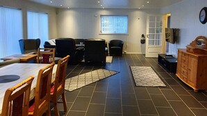 A spacious room with a dining area, a sofa, and a TV on the wall. - Lyngsalpan Cruise Lodge (Lyngen)