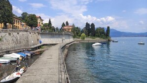 A waterfront with boats docked, a stone wall, and buildings along the shore.