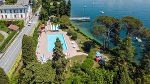 An aerial view of a resort with a swimming pool, a dock, and a road.