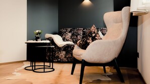 A modern room with a dark accent wall, a light-colored armchair, a small side table with a vase, and a unique patterned backdrop. - Altstadt-Hotel (Freiberg)