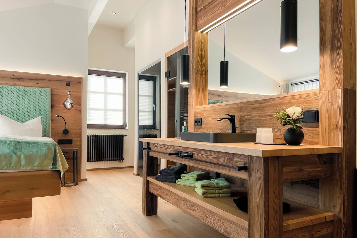 A modern bathroom with a wooden vanity, a large mirror, and a green towel rack.