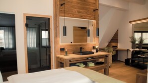 A modern bedroom with a large bed, wooden bedside tables, a built-in sink, and a large mirror. - Altstadt-Hotel (Freiberg)